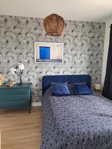 Un dormitorio con una cama azul y una pared en Les grands prés, en Aytré