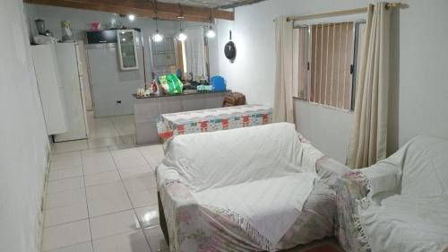 a living room with a chair and a kitchen at Casa monguagua in Mongaguá