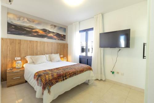 een slaapkamer met een bed en een flatscreen-tv bij Villa Piva in Playa Blanca