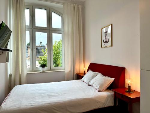 a bedroom with a bed and two windows at Pokoje Monte 26 w Sopocie in Sopot