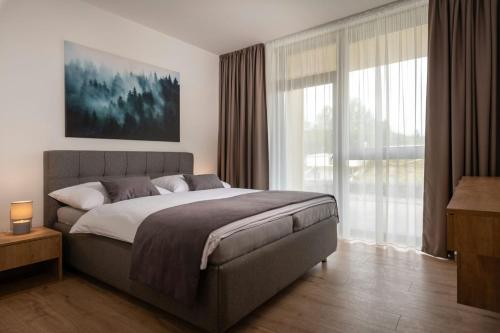 a bedroom with a large bed and a large window at DaSus Luxury Tále in Tale