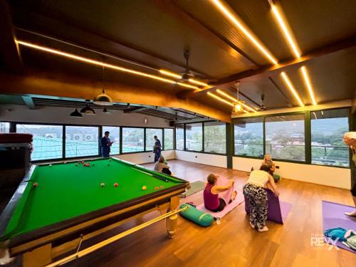 eine Gruppe von Menschen spielt Billard in einem Raum mit einem Billardtisch in der Unterkunft Green View by Green Tree Hotels in Rishikesh