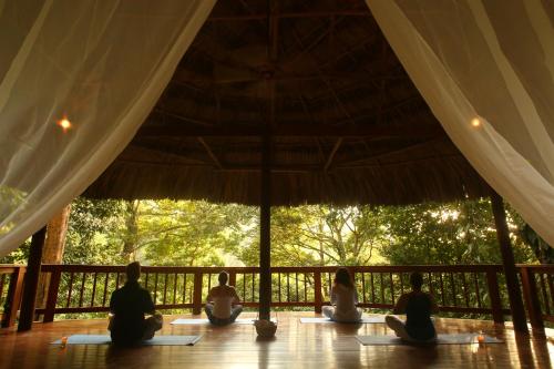 a group of people sitting on a wooden floor under an umbrella at The Lodge & Spa at Pico Bonito in El Pino