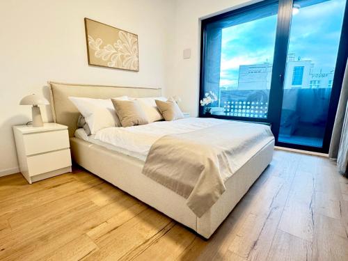 a bedroom with a bed and a large window at Peony Suite Presidential Garden Free Parking in Bratislava