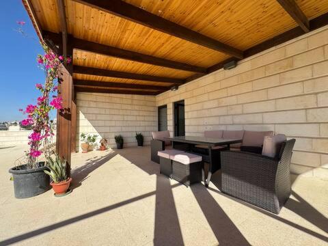 a patio with a table and chairs and flowers at Lemon Tree Residence in Amman