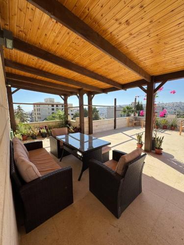 a patio with a table and chairs and a wooden roof at Lemon Tree Residence in Amman