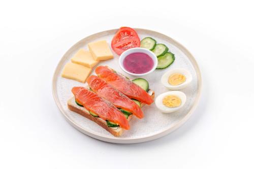 Un plato de comida con un sándwich y huevos y verduras. en Dami Almaty Hotel, en Almaty