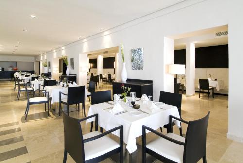 Thalassa Sousse resort & aquapark Family and couple only في سوسة: غرفة طعام مع طاولات بيضاء وكراسي سوداء