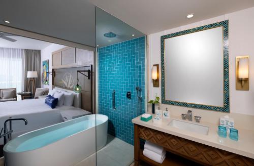 プエルト・モレロスにあるMargaritaville Island Reserve Riviera Maya - An Adults Only Karisma All-Inclusive Experienceのホテルのバスルーム(ベッド、バスタブ、シンク付)