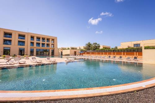 a large swimming pool with lounge chairs and a building at The Navigator - Colombus Apartments & Villas in Porto Santo