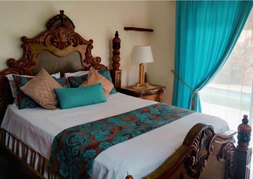 a bedroom with a bed with blue curtains and a window at Still Waters in Port Alfred