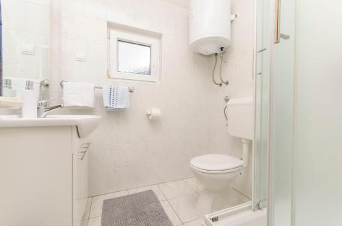 Un baño blanco con inodoro y lavabo. en Apartments Remi, en Nin