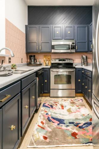 a kitchen with blue cabinets and a rug on the floor at The Chattanooga Crossroads Condo in Chattanooga