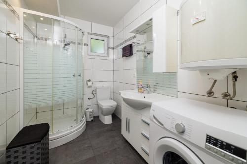 a white bathroom with a shower toilet and a sink at Villa Solterra in Grižane