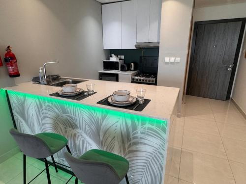 a kitchen with a counter with green chairs and a counter top at Skyleaf Studio in Dubai