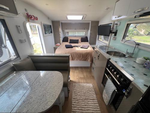 an rv kitchen with a bed and a sink at Gympie Luxury Caravan with ensuite bathroom in Tamaree