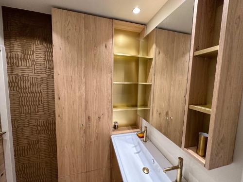 a bathroom with a white sink and wooden cabinets at Luxury 4BR Apartment with Fireplace & Private Parking - Val Thorens in Val Thorens