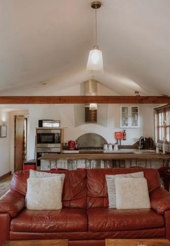 a living room with a brown leather couch at Stable lodge with Cosy Log Fire & Optional Hot tub in Horspath