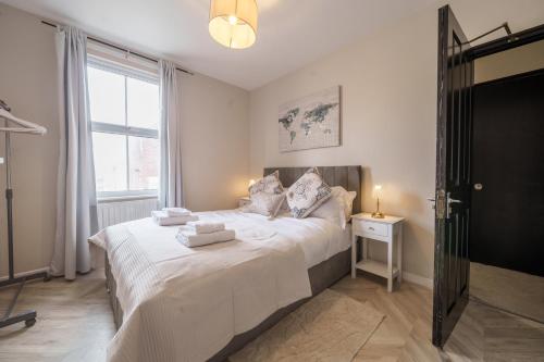 a bedroom with a bed with white sheets and a window at Oxford Modern Living - City Centre in Oxford