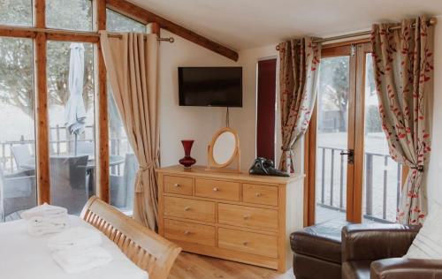 a bedroom with a dresser with a mirror and a television at Stable lodge 2 Bedrooms in Horspath