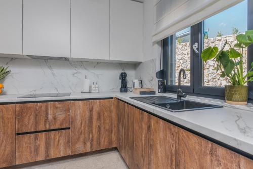Una cocina con armarios de madera y un fregadero y una ventana. en Villa Taralis with heated pool, en Kaštel