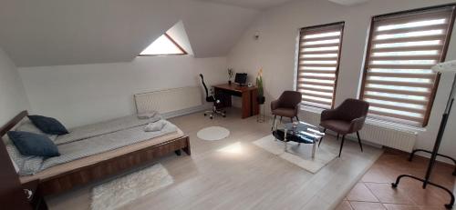 a living room with a bed and two chairs and a desk at STUDIO Apartman in Gheorgheni