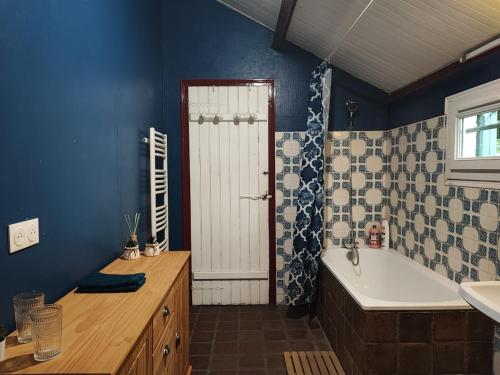 une salle de bain bleue avec une baignoire et un lavabo dans l'établissement La Tometterie - longère normande traditionnelle, à Chanteloup