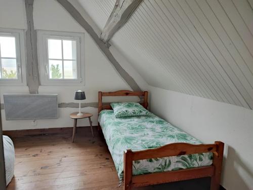 une chambre avec un lit et une table et deux fenêtres dans l'établissement La Tometterie - longère normande traditionnelle, à Chanteloup
