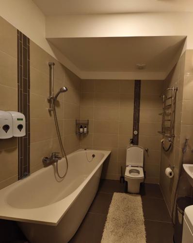 a bathroom with a bath tub and a toilet at Costa del Sol Apartment in Saulkrasti