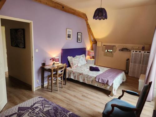 a bedroom with a bed and a table with a chair at Le prieuré in Raslay