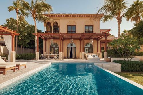 a house with a swimming pool in front of a house at One&Only The Palm Dubai in Dubai