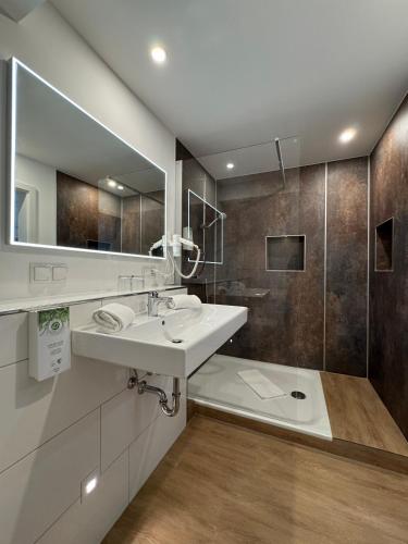 a white bathroom with a sink and a shower at PANORAMA HOTEL in Neustadt an der Weinstraße in Neustadt an der Weinstraße