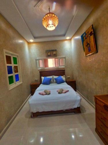 Un dormitorio con una cama y una lámpara de araña. en Appartement Moderne Tamraght plage, en Tamraght Ouzdar