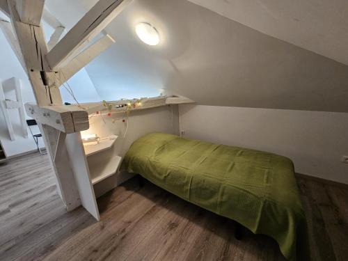 a small bedroom with a green bed and a window at Gîte du séchoir in Bouresse