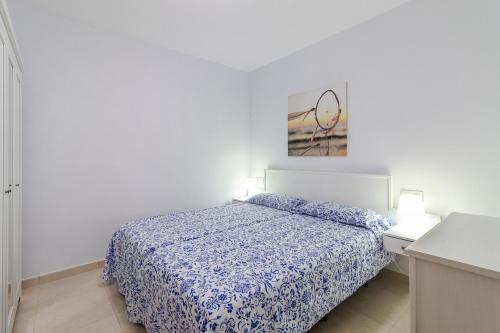Dormitorio blanco con cama con edredón azul en Arinaga Playa 2, en Agüimes