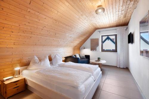 a bedroom with a large white bed and a wooden ceiling at Gästehaus Perlmuschel in Iznang