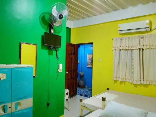 a room with a green and yellow wall with a fan at Ravara Natividad Homestay in Lucap