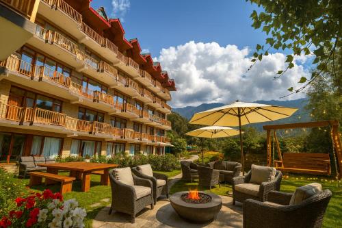 un patio del hotel con sillas y sombrilla en Himalayan Fort Resort, Manali - !! Riverside Property !! Big Garden with Campfire !! Guest Preferred !! Scenic River & Mountain View !! Big Parking !! Luxury Balcony Rooms !! Playing Zone !! Property of the Year, en Manali