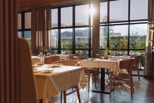 a restaurant with tables and chairs and large windows at Parkhotel Egerner Höfe in Rottach-Egern