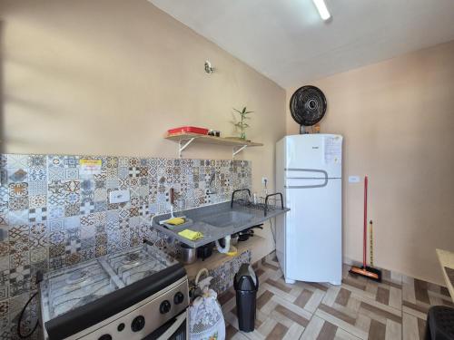 a kitchen with a white refrigerator and a sink at Residencial Via Mar - Massaguaçu in Caraguatatuba