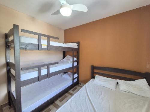 two bunk beds in a room with a ceiling fan at Residencial Via Mar - Massaguaçu in Caraguatatuba