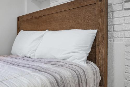 a bed with a wooden headboard and a white pillow at Pittsburgh Shadyside 1E Bright and Modern Private Bedroom with Shared Bathroom in Pittsburgh