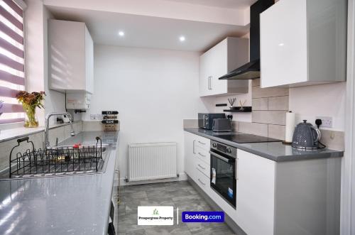 Una cocina con gabinetes blancos y encimeras negras. en 2 BDR House By Prospergress Property Short Lets & Serviced Accommodation Coventry With Free Parking and Large Garden Patio, en Coventry