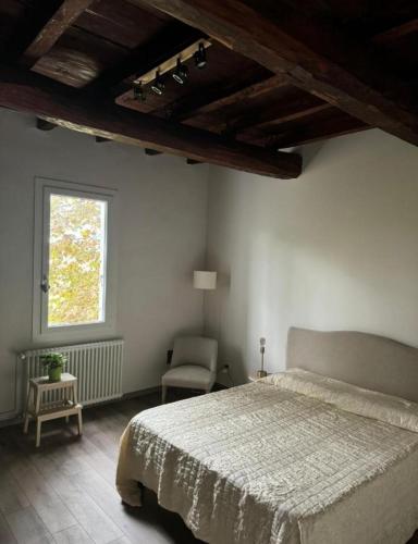 a bedroom with a bed and a window and a chair at Outlander Cottage B&B vicino Centergross Bologna in Bentivoglio