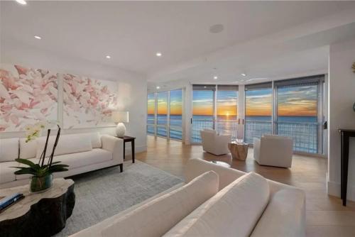 a living room with white furniture and a view of the ocean at Gulf-front Masterpiece in Naples