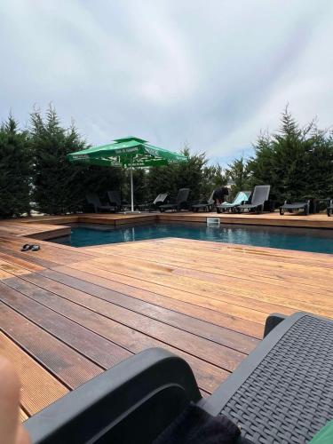 a swimming pool with a green umbrella and chairs at Планински кът in Dorkovo