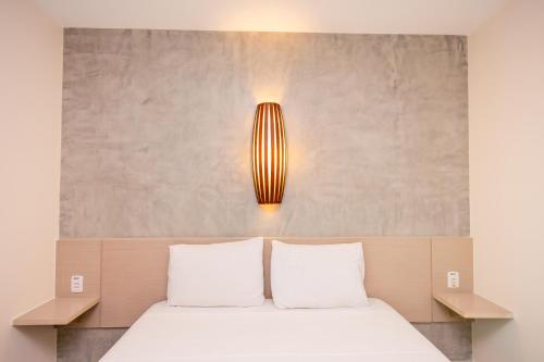 a bed with two white pillows and a light above it at Go Inn Hotel Aracaju in Aracaju