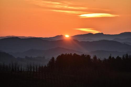 una puesta de sol sobre una cordillera con árboles en primer plano en Ca' le Stelle, 