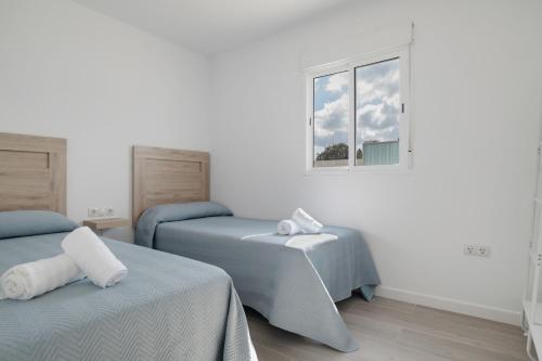 a bedroom with two beds and a window at Villa Laruma in Conil de la Frontera