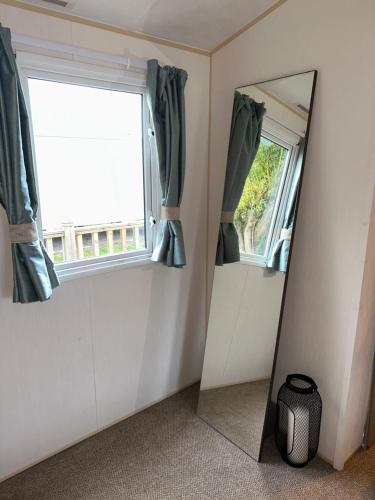 a mirror in a room with a window and curtains at Two Bedroom Caravan on 7 Lakes Country Park in Crowle